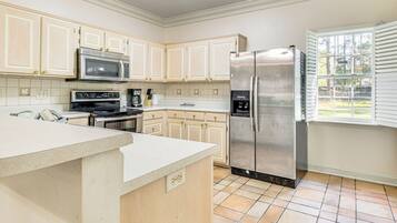 A kitchen with white cabinets, a stainless steel refrigerator, a microwave, and an oven.