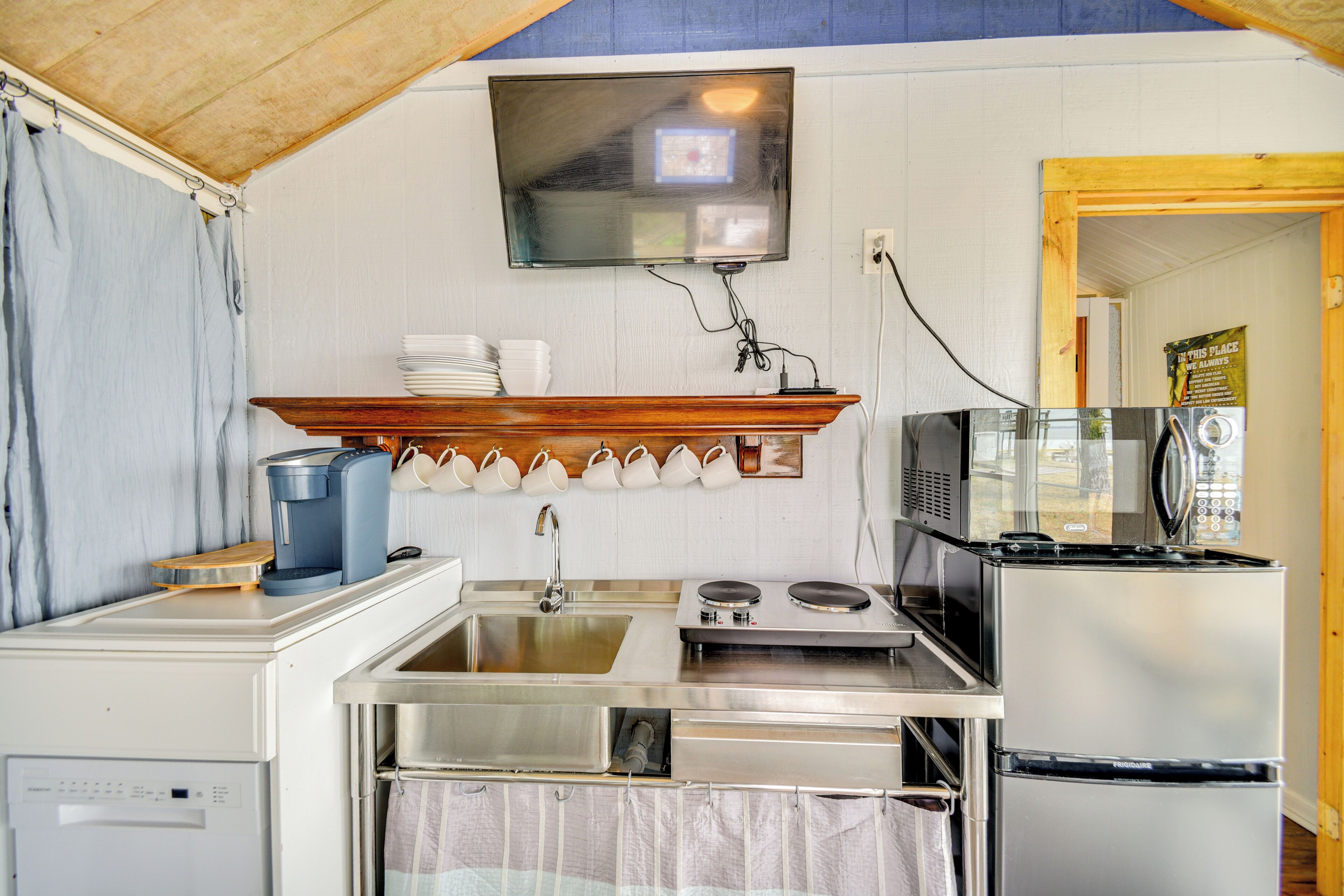 A compact kitchen with a sink, stove, microwave, and refrigerator.