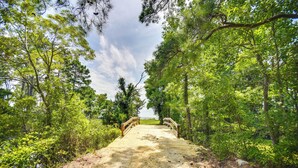 A wooden bridge leading to a sandy area surrounded by dense green foliage. - Tiny House w/ Big Views: Cabin in Shiloh! (Shiloh)
