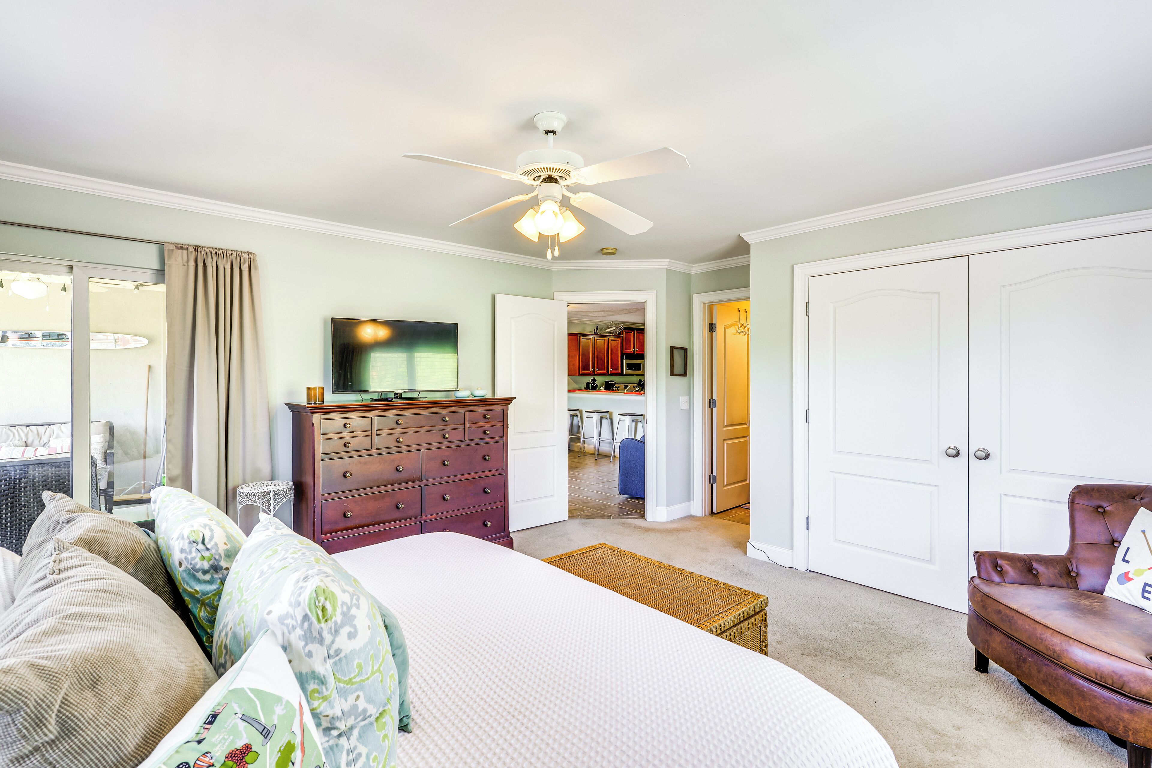 A bedroom with a bed, dresser, and a ceiling fan.