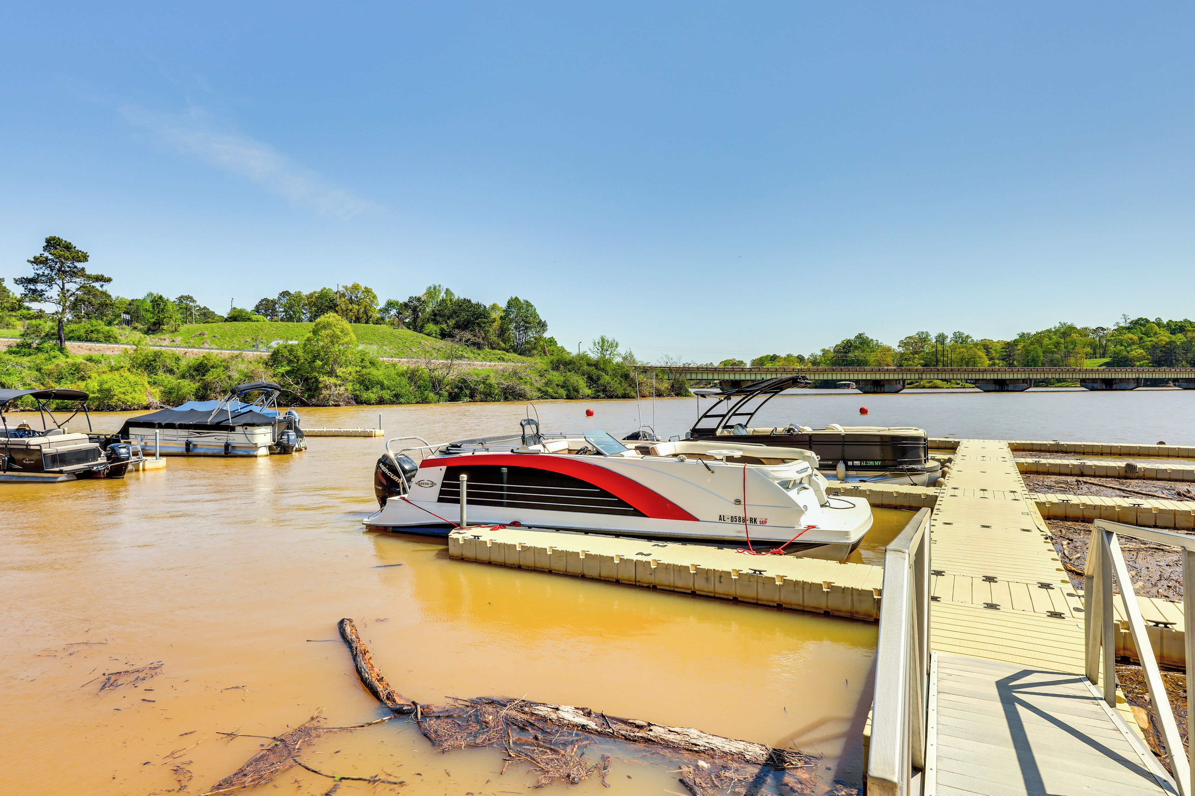 A boat docked at a pier with a clear view of the water and greenery in the background.