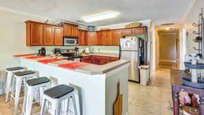 Une cuisine avec des meubles de rangement en bois, un îlot central doté de tabourets, un réfrigérateur et un four à micro-ondes.
