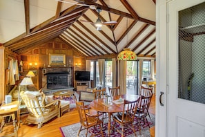 A cozy living room with a fireplace, wooden furniture, and a dining area.