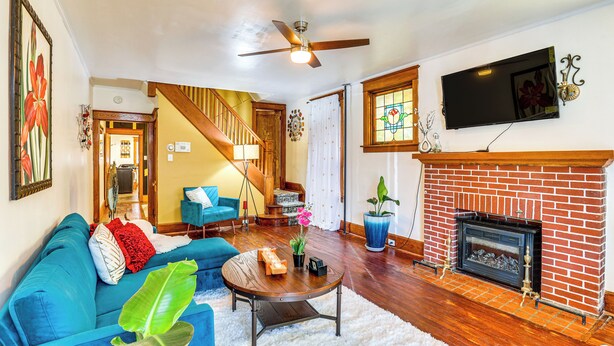 A living room with a blue sofa, a coffee table, a fireplace, and a staircase leading to another room. - 2 Mi to Dtwn: Harrisburg Escape w/ Furnished Deck! (Harrisburg)