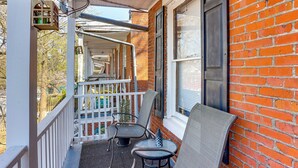 A covered porch with two chairs and a table, a brick wall, and a white railing. - 2 Mi to Dtwn: Harrisburg Escape w/ Furnished Deck! (Harrisburg)