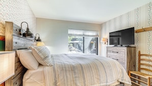 A bedroom with a bed, a television, a wooden chair, and a window with blinds. - Walk to Shops & Eats: Mammoth Lakes Condo w/ Pool (Mammoth Lakes)