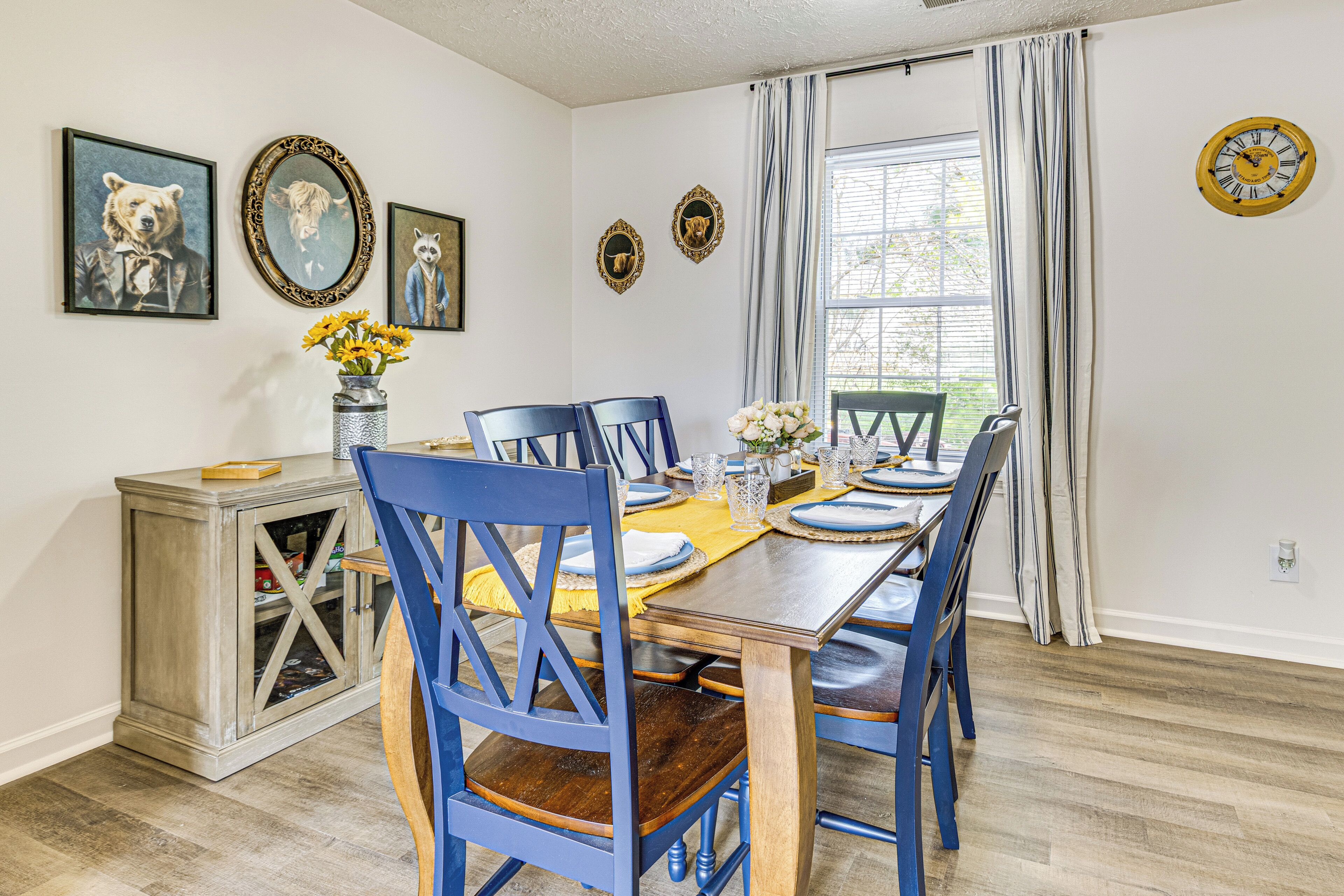 A dining room with a wooden table set for six, blue chairs, and a cabinet with a glass door.