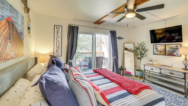 Een slaapkamer met een bed, een plafondventilator, een televisie en een schuifdeur naar een buitengebied.