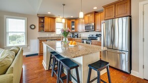 A modern kitchen with wooden cabinets, stainless steel appliances, and a central island with bar stools.