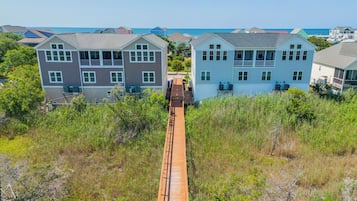 Un quartier résidentiel situé sur la côte, avec des maisons à deux étages, une promenade en bois et une vue sur l’océan.