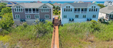 A coastal residential area with two-story houses, a wooden walkway, and a view of the ocean.