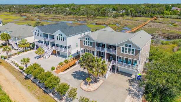 A beachfront hotel with multiple balconies, a covered walkway, and a sandy beach area.