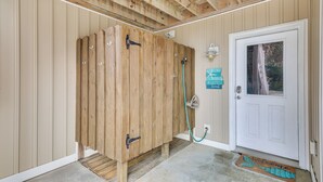 A wooden shower enclosure with a white door and a welcome mat.