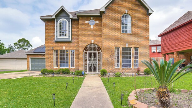 A two-story brick house with a front entrance, a garage, and a well-maintained lawn. - Home 7 Mi to Energy Corridor: Remote-work Ready! (Houston)