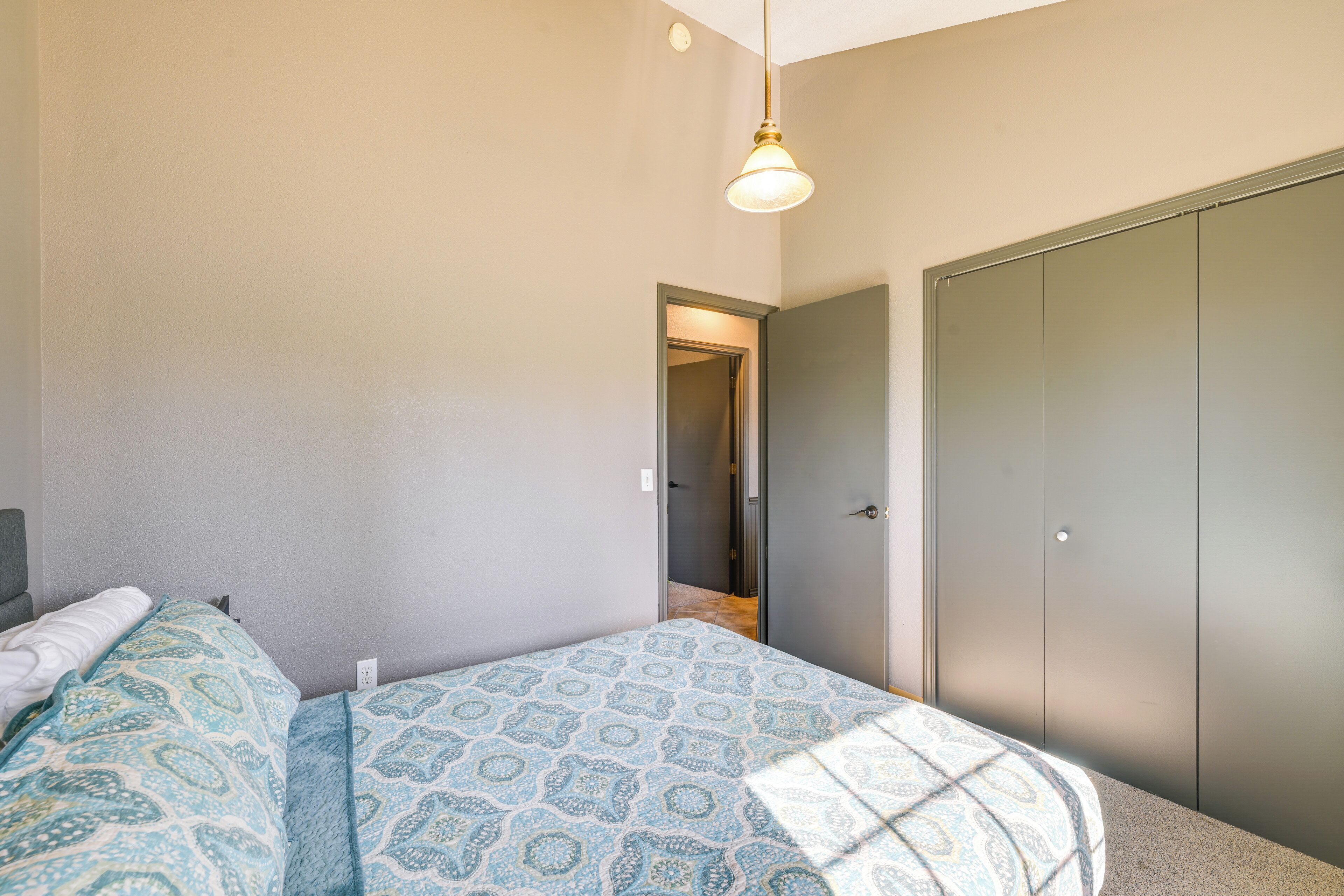 A bedroom with a bed, a wardrobe, and a door leading to another room.