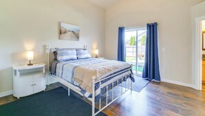 Un dormitorio con cama, mesitas de noche, ventana con cortinas y vistas al exterior.
