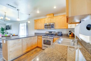 A modern kitchen with wooden cabinets, granite countertops, stainless steel appliances, and a central island. - 3 Mi to Riverside Park: Grants Pass Getaway! (Grants Pass)