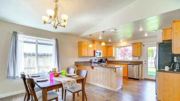 Una cocina moderna con armarios de madera, una isla central y una zona de comedor con mesa y sillas.