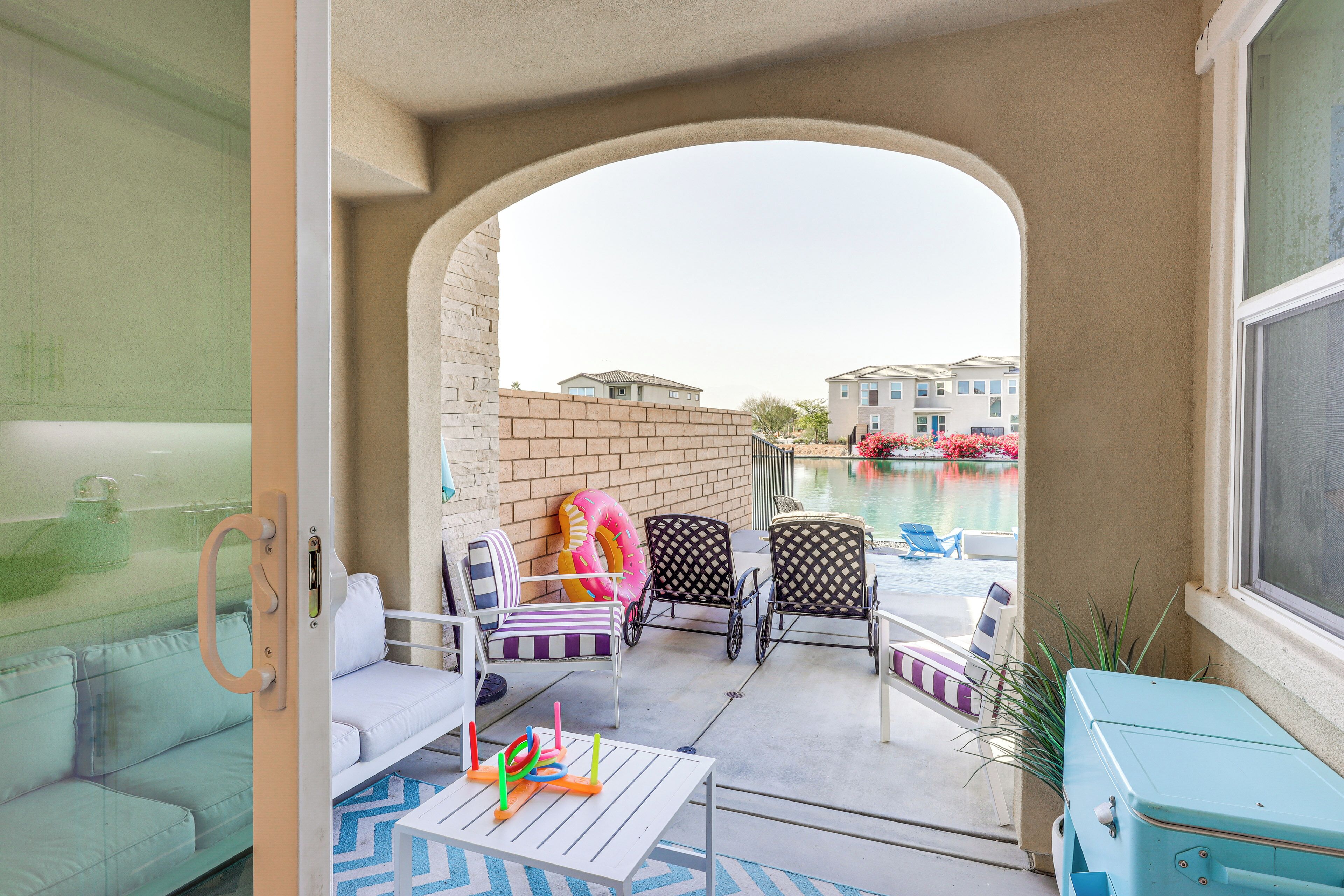 Un balcón con vista a una piscina, mobiliario exterior y un muro de ladrillo.