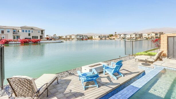 A poolside area with lounge chairs and a view of a residential complex.