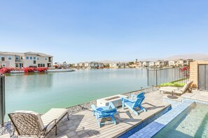 A poolside area with lounge chairs and a view of a residential complex. - Luxe Indio Lake House 7 Mi to Coachella! (Indio)