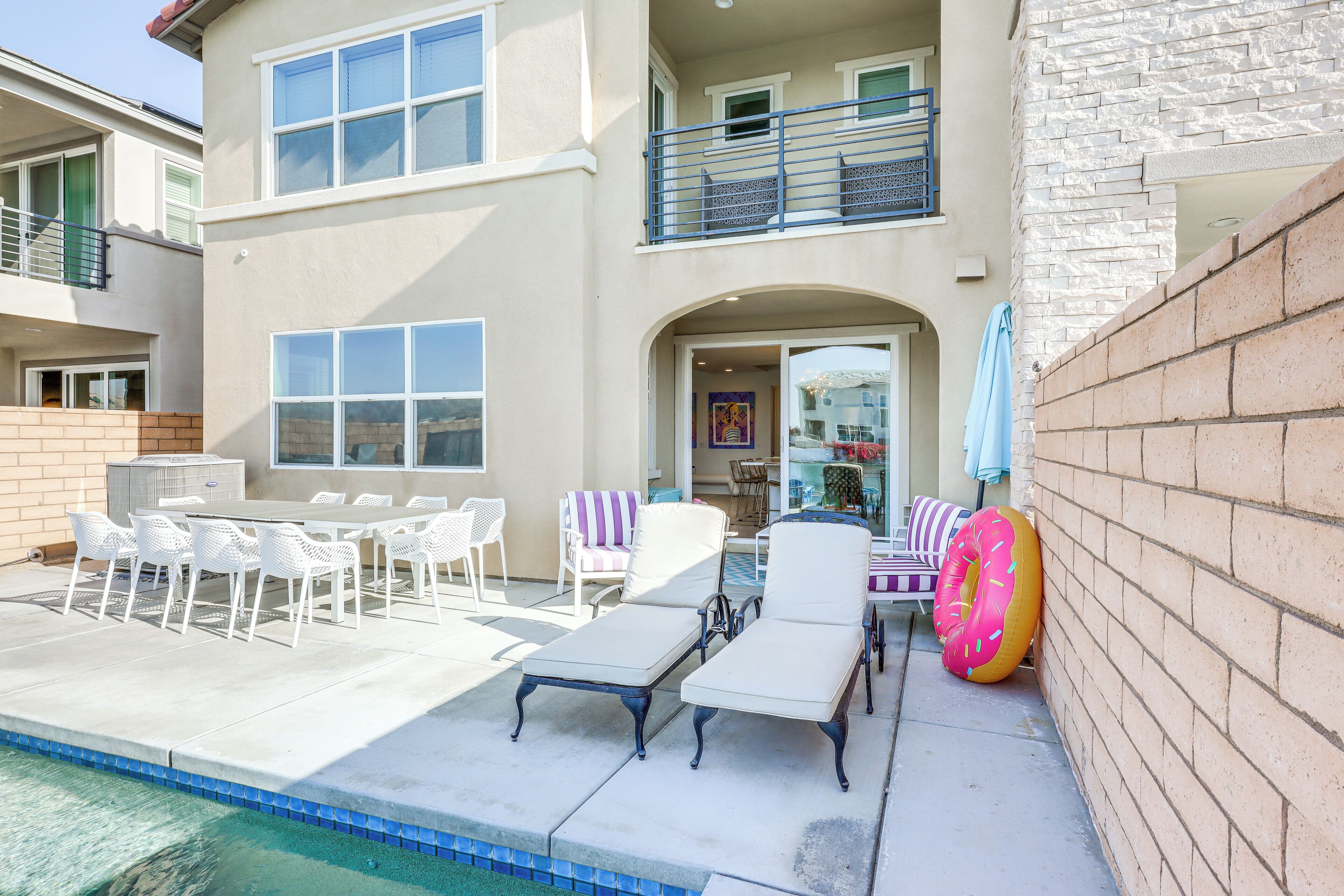 Une maison à deux étages dotée d’un patio aménagé avec des meubles d’extérieur et une piscine.