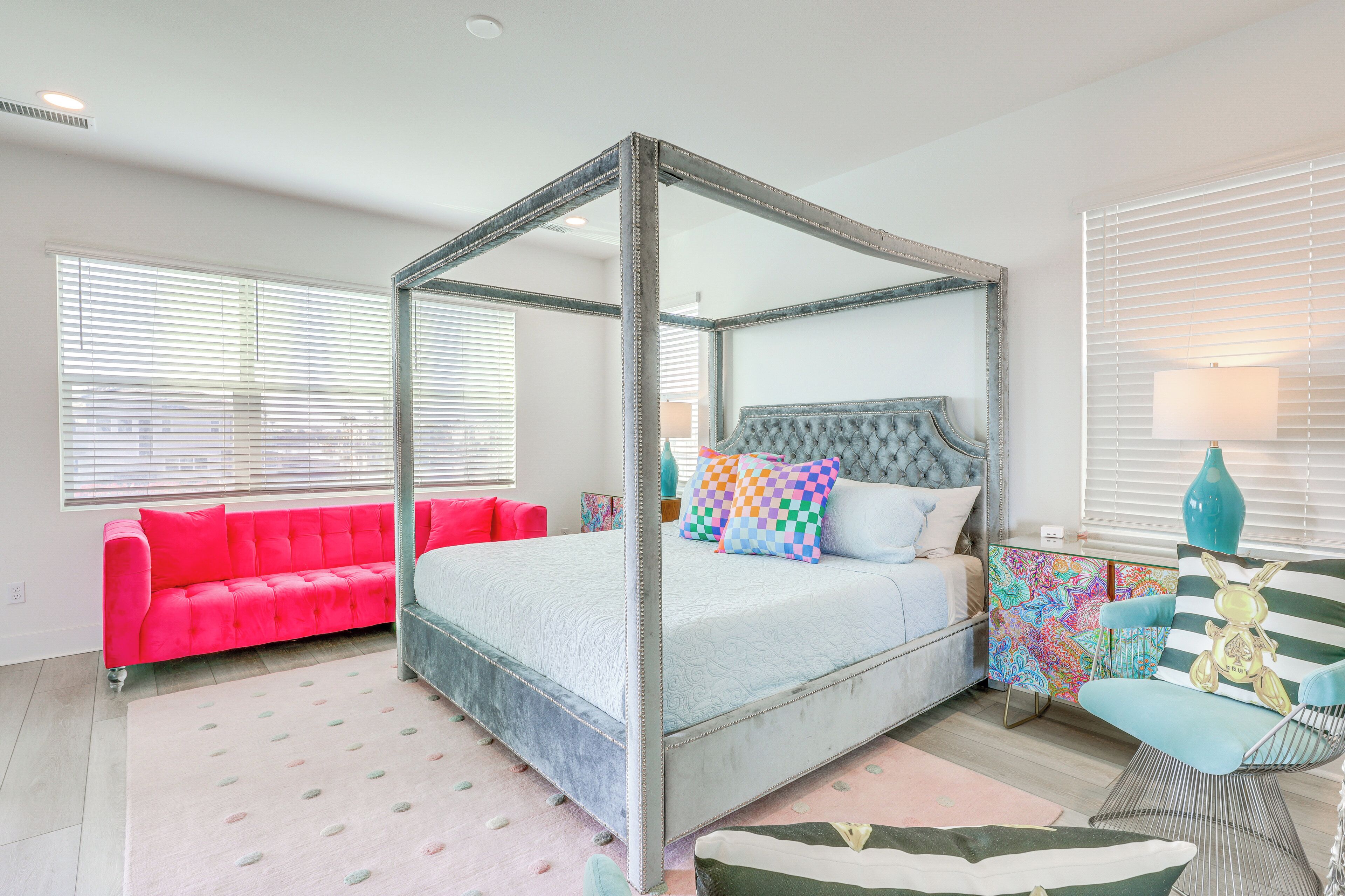 Une chambre à coucher avec un lit à baldaquin, un canapé rouge et une commode aux couleurs vives.