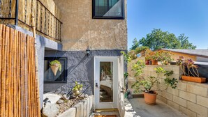 Un immeuble résidentiel doté d’une entrée accueillante, d’un petit jardin agrémenté de plantes en pot et d’une clôture en bambou.