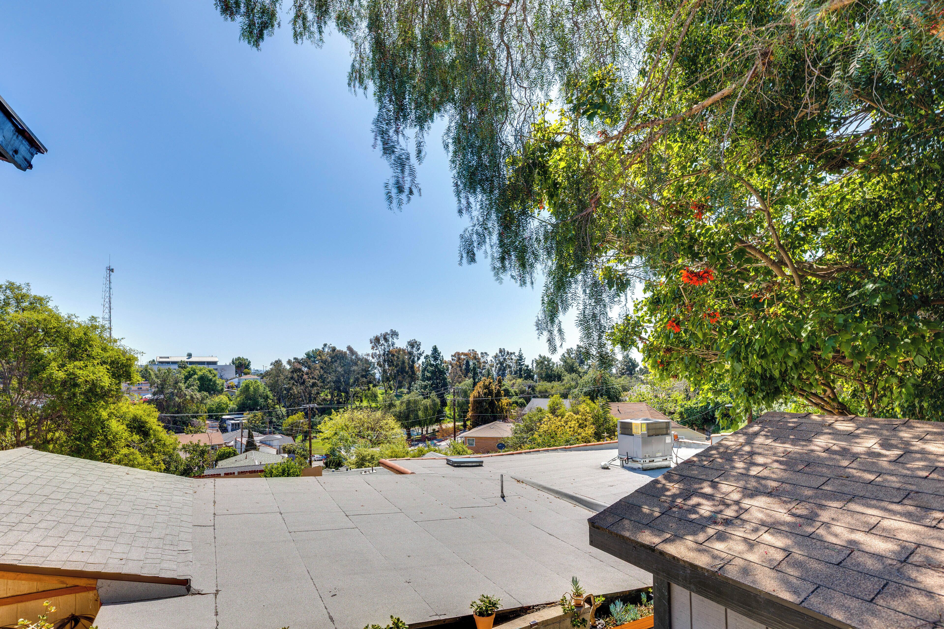 A rooftop with a clear view of the surrounding neighborhood, including houses and trees.
