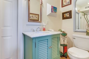 A bathroom with a white toilet, a blue cabinet with a mirror above the sink, and a framed picture on the wall. - 2 Docks + Paddleboard: Lakefront Alabama Retreat! (Trussville)