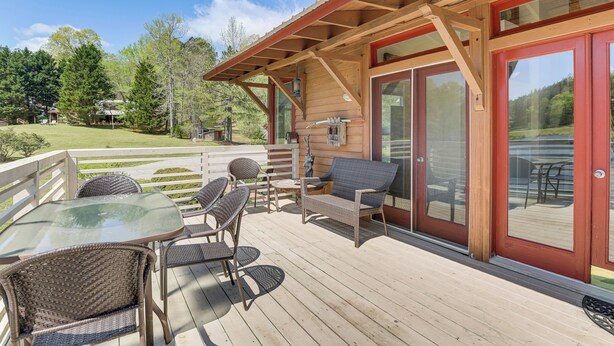 A wooden deck with wicker furniture, a glass table, and a red door with glass panels. - 2 Docks + Paddleboard: Lakefront Alabama Retreat! (Trussville)
