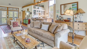 A spacious living room with a large beige sofa, a wooden coffee table, and a dining area with a kitchen in the background. - 2 Docks + Paddleboard: Lakefront Alabama Retreat! (Trussville)
