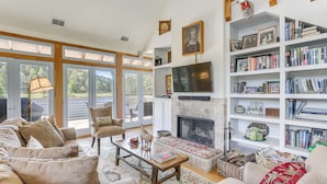 A spacious living room with a fireplace, a large bookshelf, and a comfortable seating area. - 2 Docks + Paddleboard: Lakefront Alabama Retreat! (Trussville)