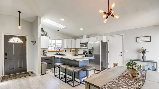 Una cocina moderna con una isla central, taburetes de bar y una mesa de comedor.