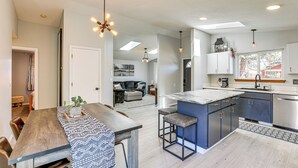 Una cocina moderna con una isla central, electrodomésticos integrados y una zona de comedor con mesa y sillas de madera.