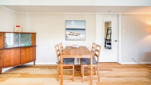 Un comedor con una mesa y sillas de madera, un aparador con puerta de vidrio y un cuadro en la pared.
