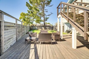 A wooden deck with wicker furniture, a staircase, and a view of a green lawn and trees. - Walk to Poplar Beach: Cozy Coastal Getaway w/ Yard (Half Moon Bay)