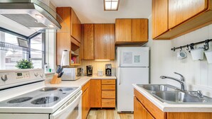 Una cocina compacta con armarios de madera, horno empotrado, refrigerador y pileta.