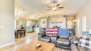 A spacious living room with a leather couch, wooden coffee table, and a dining area with a chandelier. - Outdoor Entertaining Space: Family Home in Milton (Milton)