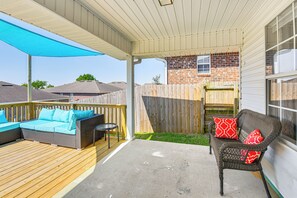 A covered patio with a wooden deck, two wicker sofas with cushions, and a small table. - Outdoor Entertaining Space: Family Home in Milton (Milton)