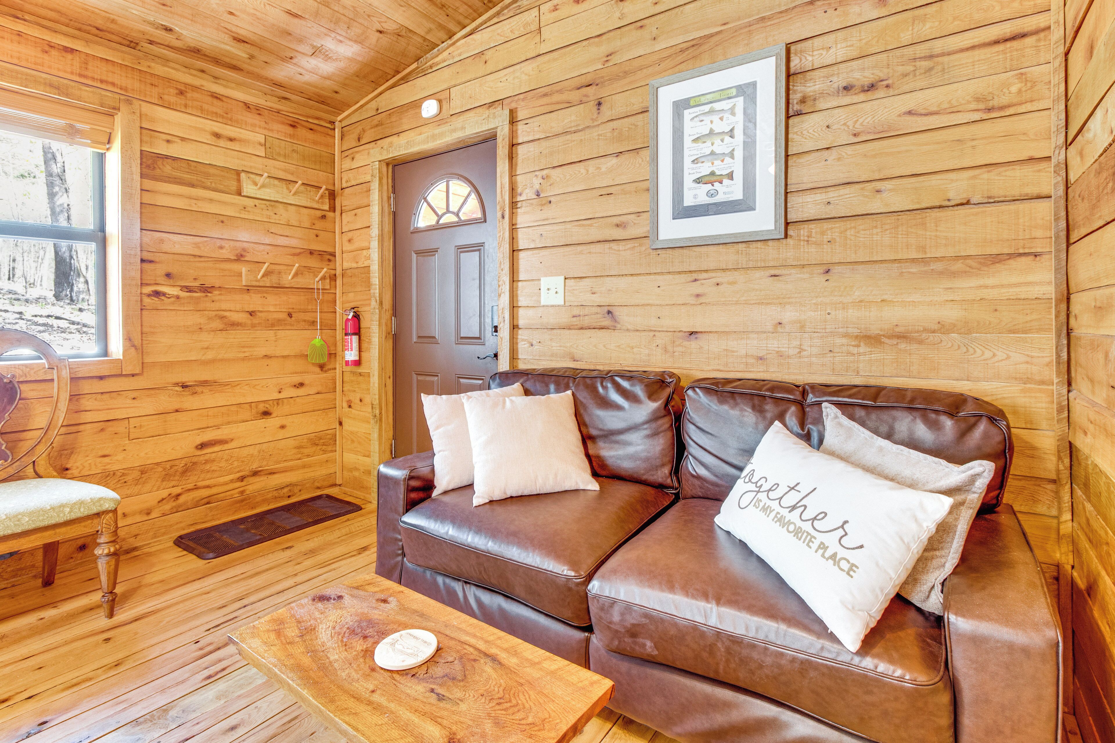 A wooden cabin interior with a brown leather sofa, a wooden bench, and a small table.