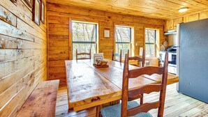 Interno di una baita in legno con un tavolo da pranzo, sedie e angolo cottura.