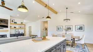 A spacious kitchen with a large island, dark cabinetry, and modern pendant lighting. - Patio + Outdoor Dining: Modern Home in Paradise (Paradise)