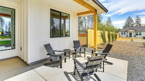A covered patio with outdoor seating and large windows. - Patio + Outdoor Dining: Modern Home in Paradise (Paradise)