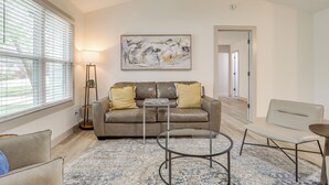 A modern living room with a leather sofa, a glass coffee table, a patterned rug, and a minimalist painting on the wall. - < 1 Mi to Main St & Amphitheater: Woodstock Home! (Woodstock)