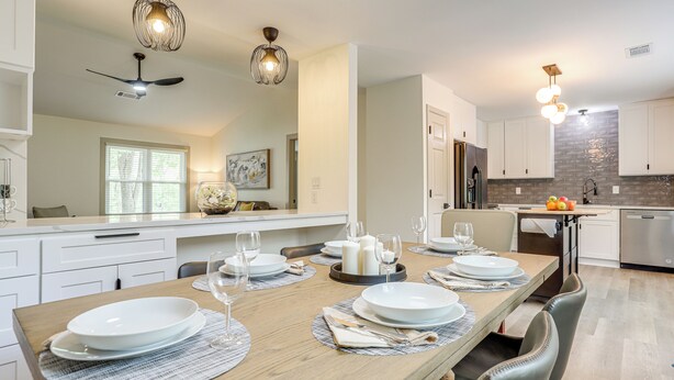 A modern kitchen with white cabinetry, a wooden dining table set for six, and a brick backsplash. - < 1 Mi to Main St & Amphitheater: Woodstock Home! (Woodstock)