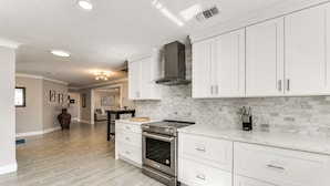 A modern kitchen with white cabinets, a stainless steel oven, and a tiled backsplash. - Waterfront Retreat w/ Pool & Yard in Sarasota (Sarasota)