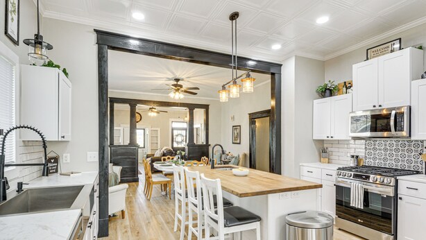 A modern kitchen with white cabinetry, a wooden island, and a built-in stove.