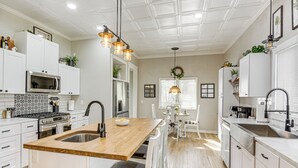 A modern kitchen with white cabinetry, a wooden island with a sink, and pendant lighting.