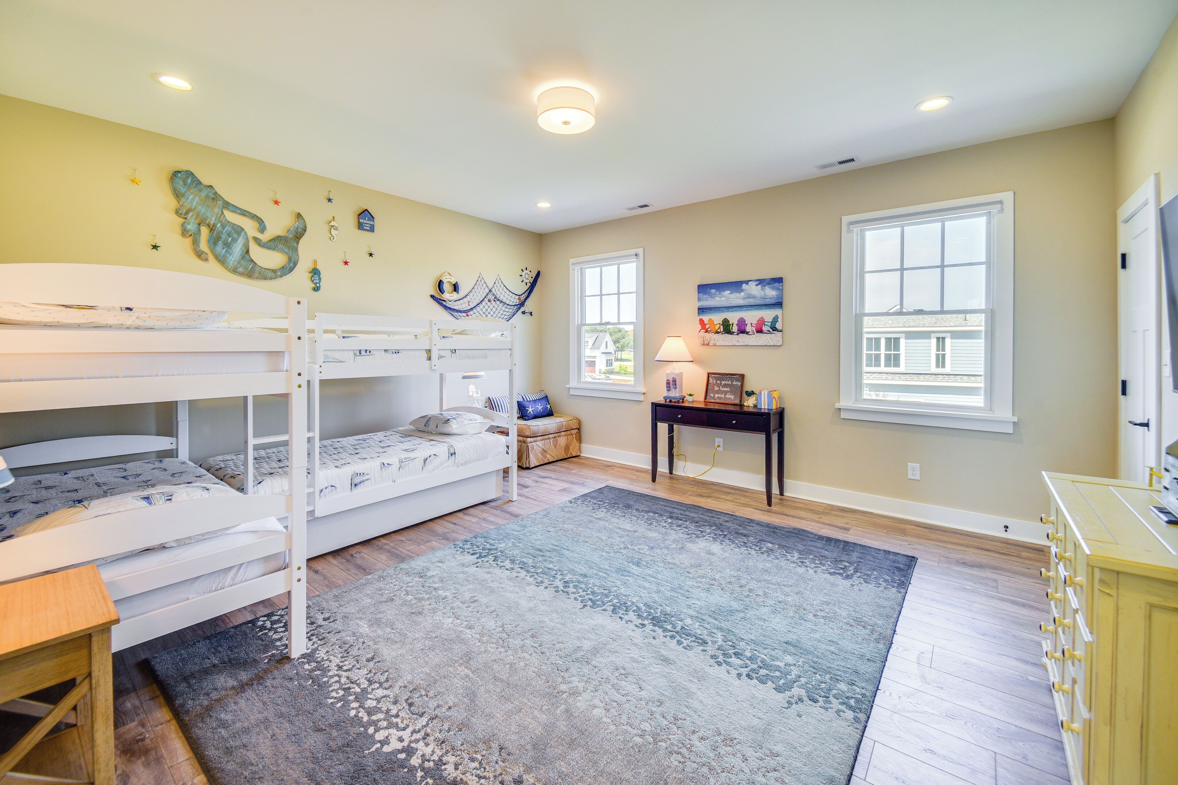 A bedroom with bunk beds, a desk, and a rug.
